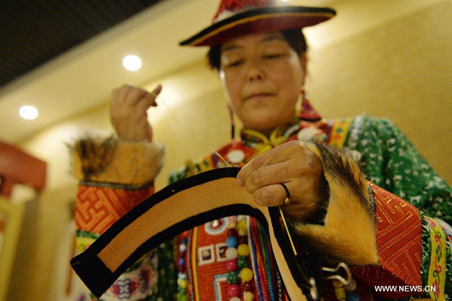 Inheritor Yang Hongmei makes traditional clothing of Yugu ethnic group at a studio in Sunan Yugu Autonomous County of northwest China's Gansu Province, July 30, 2015. Various studios were set by local government this year to preserve and promote Yugu ethnic group's intangible cultural heritages, such as ballads, embroidery and wedding customs. (Xinhua/Chen Bin) 