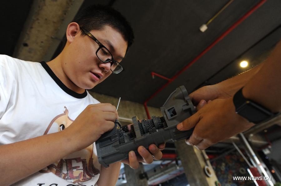 Gao Hua examines a 3D printer at a workshop of the Baidu Pioneer Park in Changchun, capital of northeast China's Jilin Province, July 30, 2015. Graduated from Jilin University, Gao Hua and Hou Xiaoye are both enthusiasts in science and technology. Getting bored with average work, they founded their geek studio which undertakes innovation of gadgets such as 3D printers, drones and wearable virtual reality headsets that they believe can change people's everyday life. (Xinhua/Zhang Nan) 