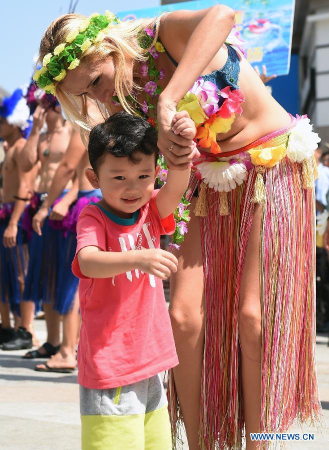 A foreign artist teaches a child to dance during a Hawaii-styled water festival in Changchun, capital city of northeast China's Jilin Province, Aug. 3, 2015.