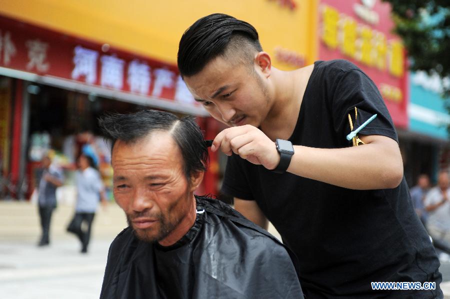 Barber Hong Tao gives a homeless man free haircuts at the railway station in Zhengzhou, capital of central China's Henan Province, Aug. 4, 2015. 