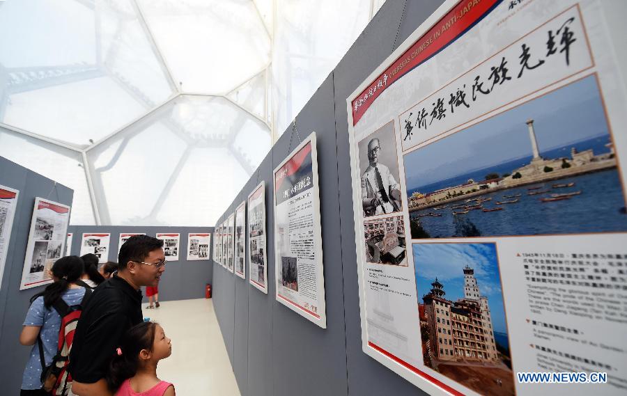 People visit a photo exhibition with the theme of 'Overseas Chinese and the Chinese People's War of Resistance against Japanese Aggression' at National Aquatics Center in Beijing, capital of China, Aug. 4, 2015.
