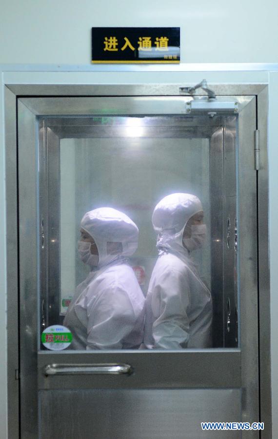 Workers get through an air shower room berfor entering package workshops to pack up high-speed railway bentos in a factory in Xiaolan Economic Development Zone in Nanchang County, east China's Jiangxi Province, Aug. 4, 2015.