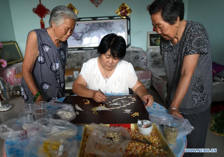 Farmer Yu Huanxin makes a handicraft with seeds of different kind in Damengqiao Village, Dacheng County of Langfang city, north China's Hebei Province, Aug. 5, 2015. 