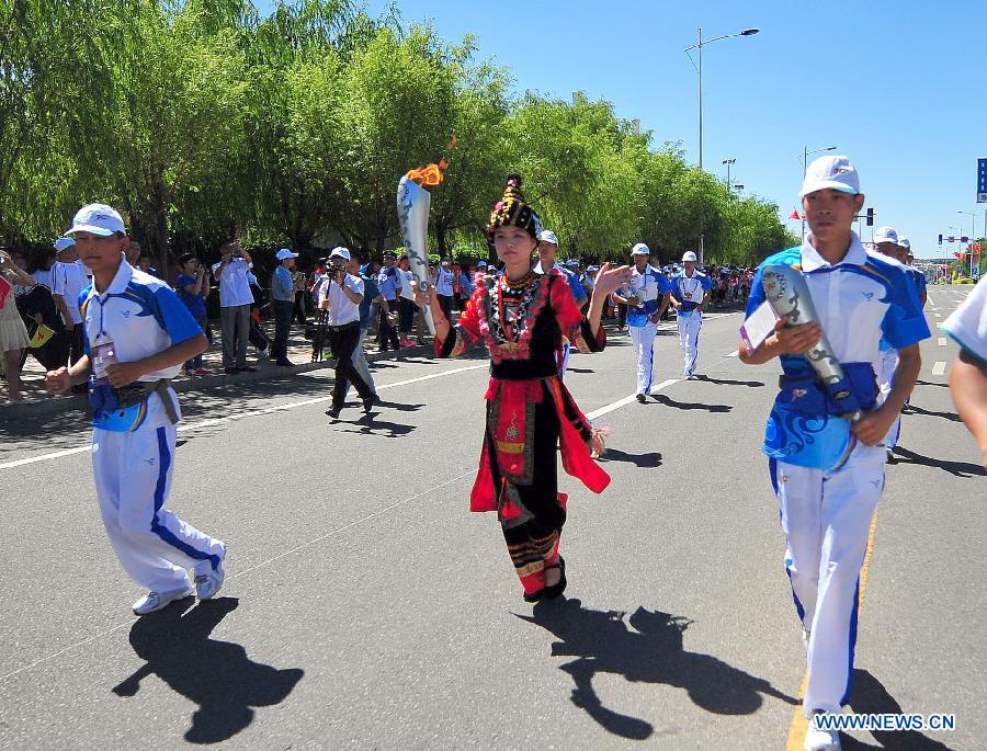 Torch bearer Dong Xuyang of Yao ethnic group runs in the torch relay of the 10th Chinese Traditional Games of Ethnic Minorities in Erdos, Inner Mongolia Autonomous Region, China on Aug. 6, 2015.