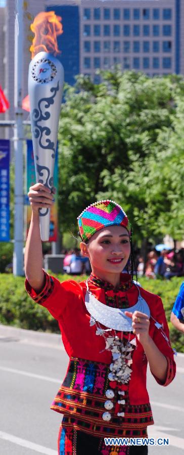 Torch bearer Huang Zhengsi of Li ethnic group runs in the torch relay of the 10th Chinese Traditional Games of Ethnic Minorities in Erdos, Inner Mongolia Autonomous Region, China on Aug. 6, 2015. 