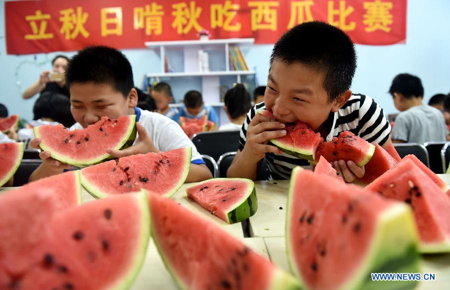 Children eat watermelons to meet the coming solar term 'beginning of autumn' in Hefei, capital of east China's Anhui Province, Aug. 7, 2015. 