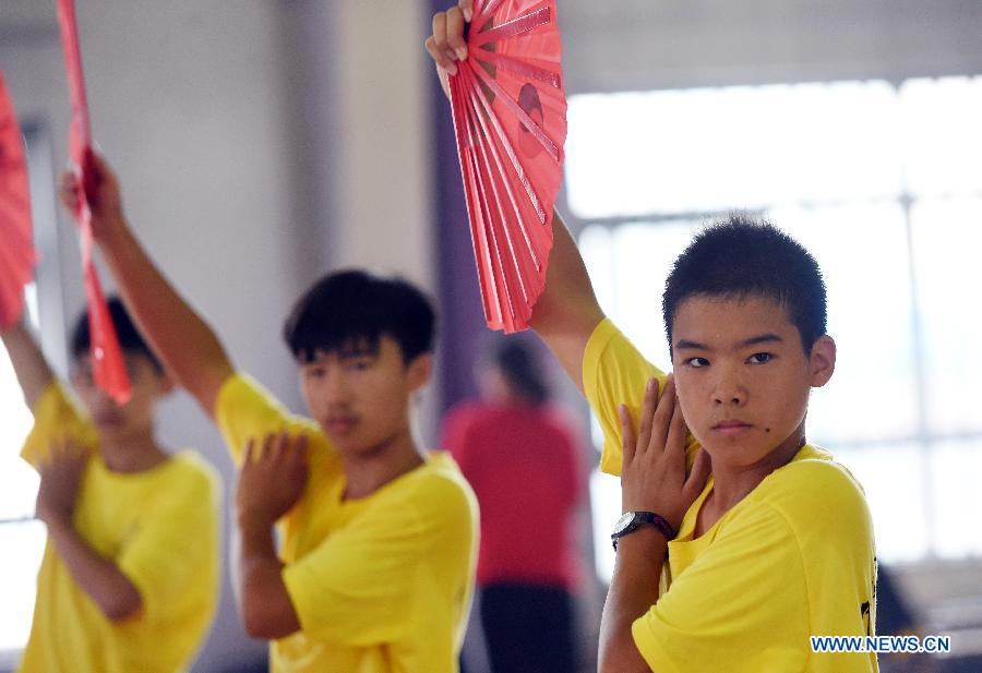 Overseas Chinese youth learn to perform Kung Fu Fan during the 'Chinese Root-Seeking Tour' Summer Camp in Beijing, capital of China, Aug. 7, 2015.