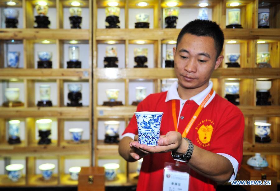An exhibitor shows a Jingdezhen tea ware at a folk art exhibition in Changchun International Convention and Exhibition Center in Changchun, northeast China's Jilin Province, Aug. 7, 2015. 