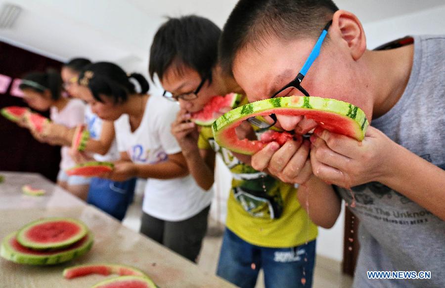 Young people take part in a watermelon-eating competition to meet the coming solar term 'beginning of autumn' in Nantong, east China's Jiangsu Province, Aug. 7, 2015. 