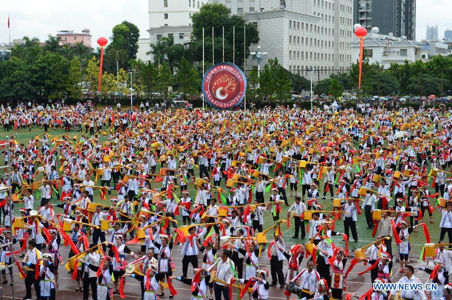 Axi people, a branch of the Yi ethnic group, perform their folk dance named 'Axi Tiaoyue', or 'Axi Dance under Moonlight', in the stadium of Mile, southwest China's Yunnan Province, Aug. 7, 2015. 