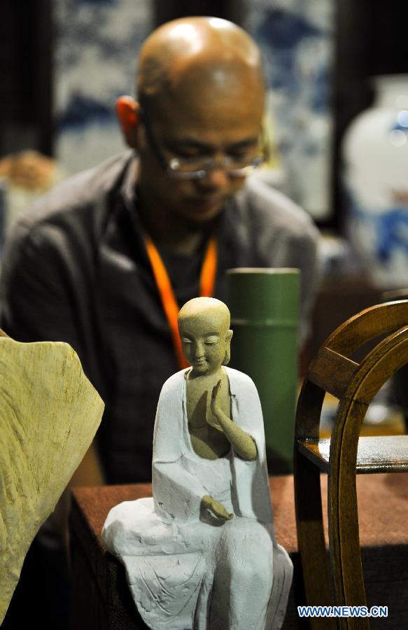 An exhibitor arranges art works at a folk art exhibition in Changchun International Convention and Exhibition Center in Changchun, northeast China's Jilin Province, Aug. 7, 2015. 