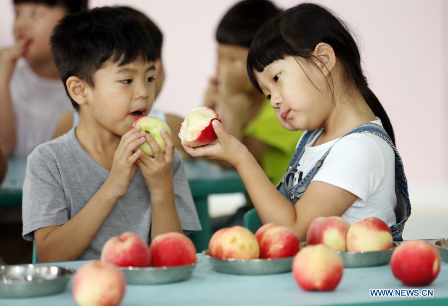 Children eat peaches to meet the coming solar term 'beginning of autumn' at a kindergarten in Tancheng County in Linyi, east China's Shandong Province, Aug. 7, 2015.