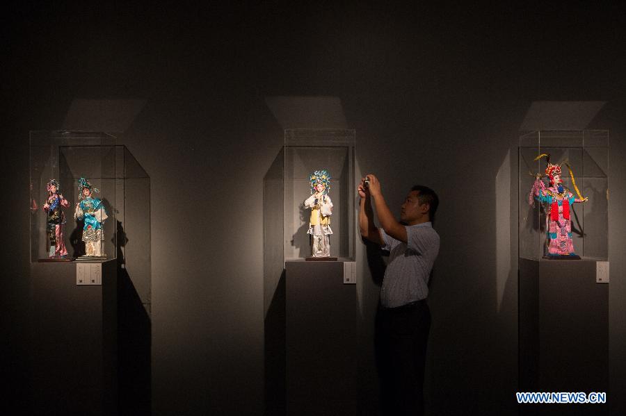 A visitor takes photos of a silk figurine during an exhibition in Beijing, capital of China, Aug. 7, 2015.