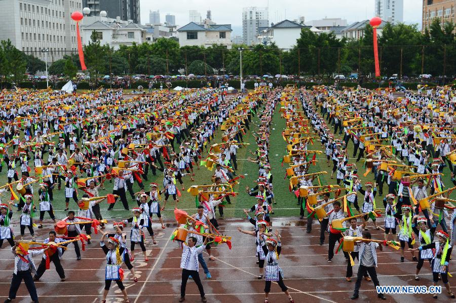 Axi people, a branch of the Yi ethnic group, perform their folk dance named 'Axi Tiaoyue', or 'Axi Dance under Moonlight', in the stadium of Mile, southwest China's Yunnan Province, Aug. 7, 2015. 