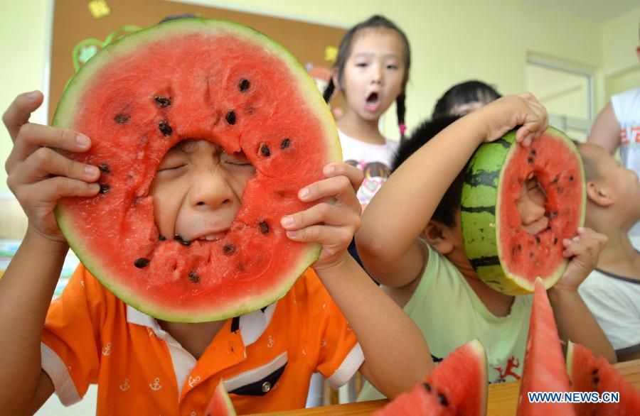 Children eat watermelons to meet the coming solar term 'beginning of autumn' at a kindergarten in Handan, north China's Hebei Province, Aug. 7, 2015. 