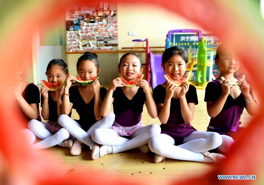 Children eat watermelons to meet the coming solar term 'beginning of autumn' at Hongning Dancing School in Bozhou, east China's Anhui Province, Aug. 7, 2015.