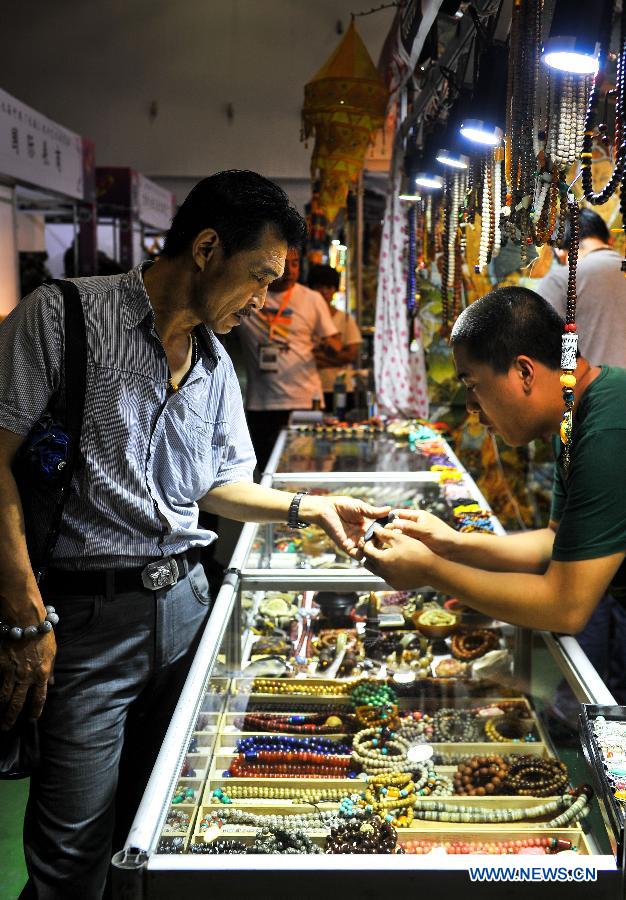 A customer selects art works at a folk art exhibition in Changchun International Convention and Exhibition Center in Changchun, northeast China's Jilin Province, Aug. 7, 2015. 