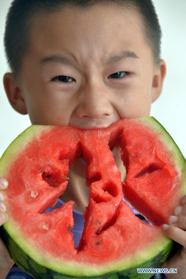 A child eats watermelons to meet the coming solar term 'beginning of autumn' in Liaocheng, east China's Shandong Province, Aug. 6, 2015.