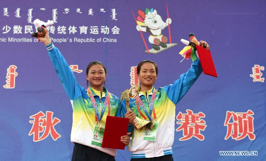 Wu Anzhen (R) and Fei Qianhong from central China's Hunan Province wave to the audience at an awarding ceremony after winning a doule game of swing during the 10th National Traditional Games of Ethnic Minorities of China in Ordos, north China's Inner Mongolia Autonomous Region, Aug. 10, 2015. 