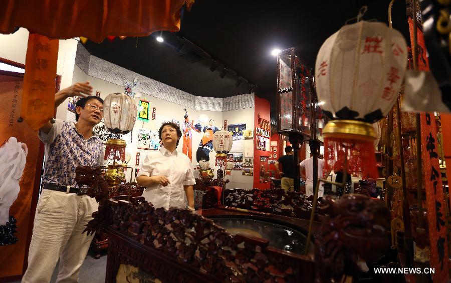 Visitors look at objects used in a traditional music concert at the new exhibition hall of intangible cultural heritage in Hongqiao District of Tianjin, north China, Aug. 11, 2015. 