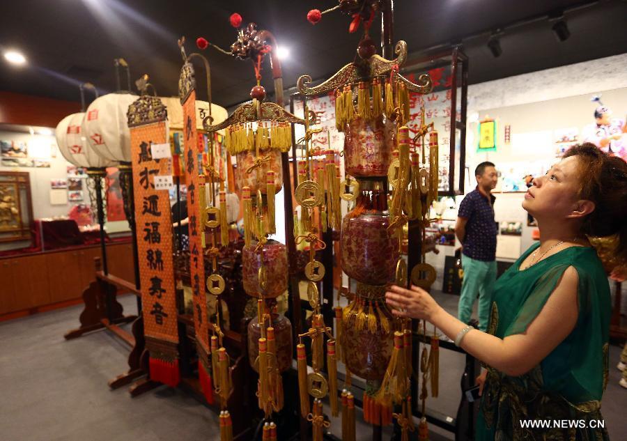 A woman looks at lamps which have a history of hundreds of years at the new exhibition hall of intangible cultural heritage in Hongqiao District of Tianjin, north China, Aug. 11, 2015.