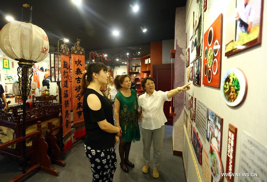Visitors listen to the introduction of the traditional snacks of Tianjin at the new exhibition hall of intangible cultural heritage in Hongqiao District of Tianjin, north China, Aug. 11, 2015. 