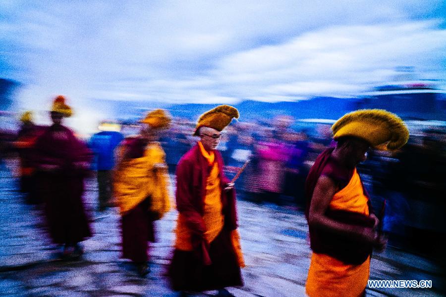 Monks head for the venue for a ceremony of unfolding a huge Thangka Buddha portrait at Drepung Monastery in Lhasa, capital of southwest China's Tibet Autonomous Region, Aug. 14, 2015.