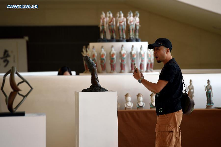 A visitor appreciates sculptures at Gansu Theater in Lanzhou, capital of northwest China's Gansu Province, Aug. 17, 2015.