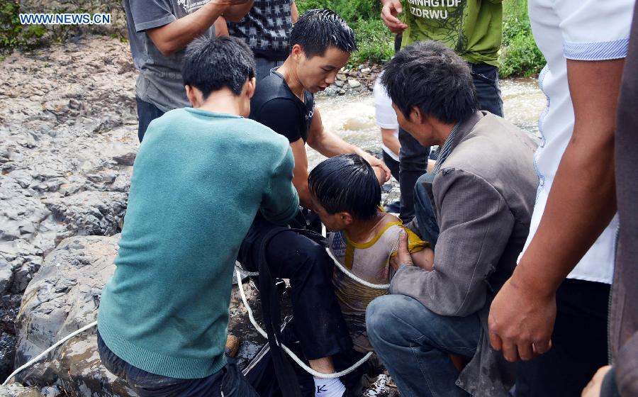 People rescue a boy at Diaoshui Village of Mazha Town in Weining County, southwest China's Guizhou Province, Aug. 16, 2015. 