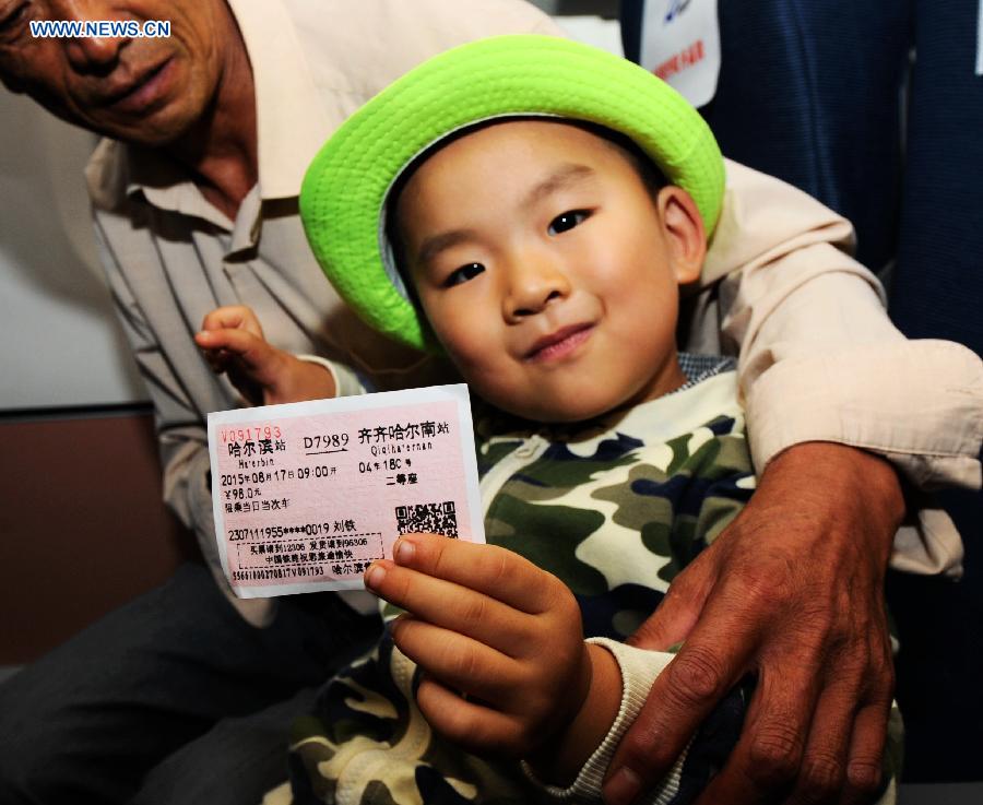 A boy shows the ticket on the high-speed train D7989, northeast China's Heilongjiang Province, Aug. 17, 2015. 