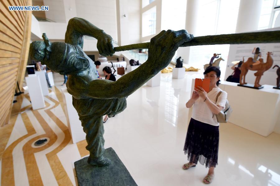 A visitor takes photos of sculptures at Gansu Theater in Lanzhou, capital of northwest China's Gansu Province, Aug. 17, 2015. 