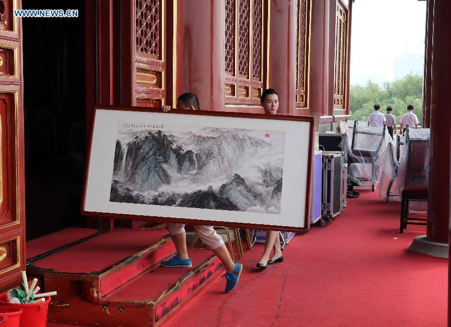 A staff worker carries a Chinese painting work at the Tian'anmen Rostrum in Beijing, capital of China, Aug. 17, 2015.