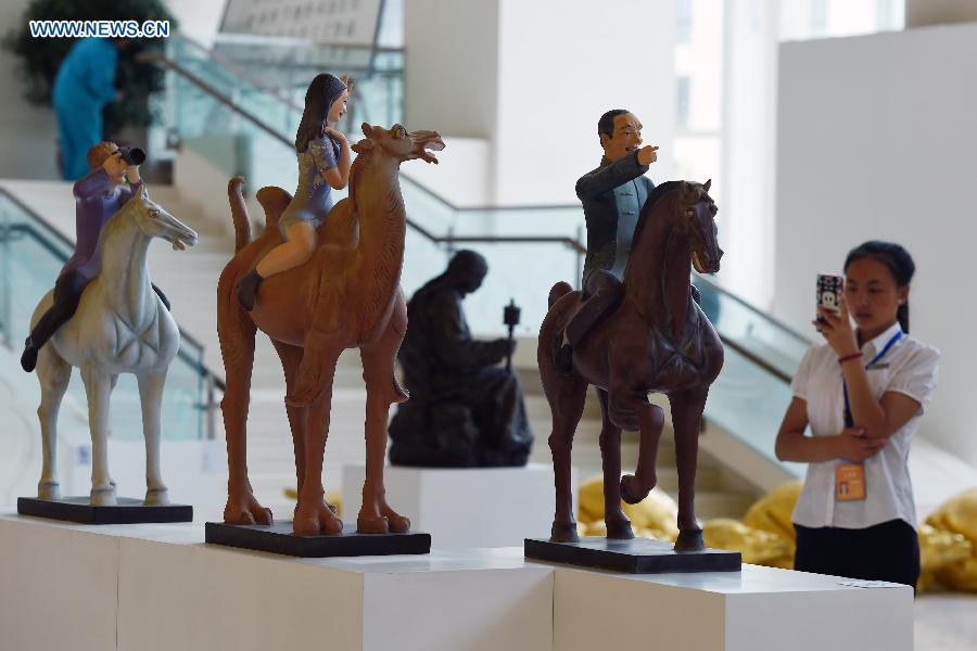 A woman appreciates sculptures at Gansu Theater in Lanzhou, capital of northwest China's Gansu Province, Aug. 17, 2015. 