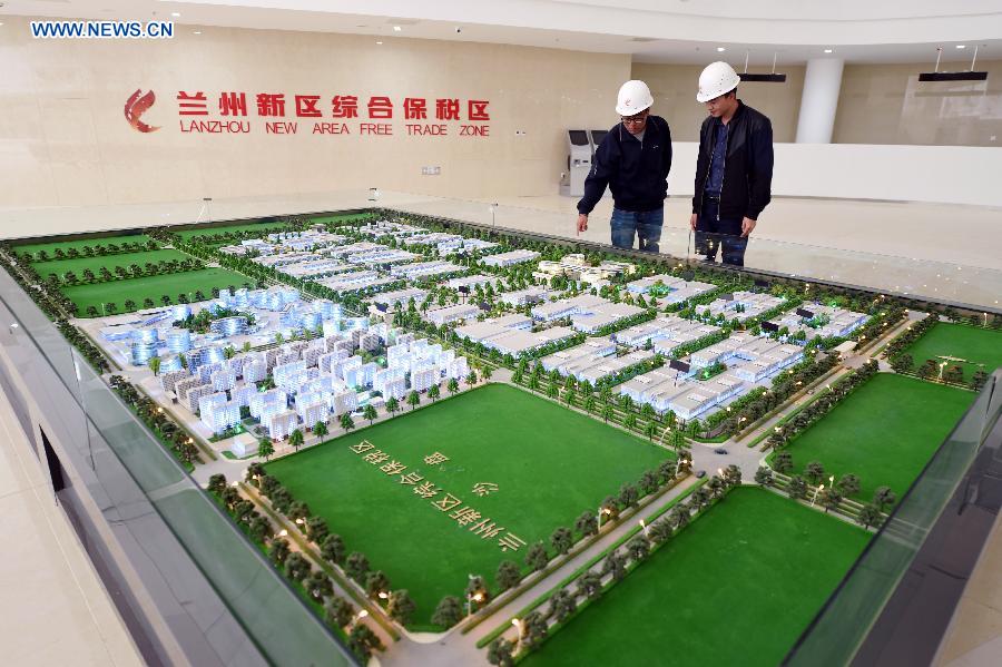 Workers look at the sand table of the Lanzhou New Area Free Trade Zone in Lanzhou, capital of northwest China's Gansu Province, Aug. 18, 2015. 