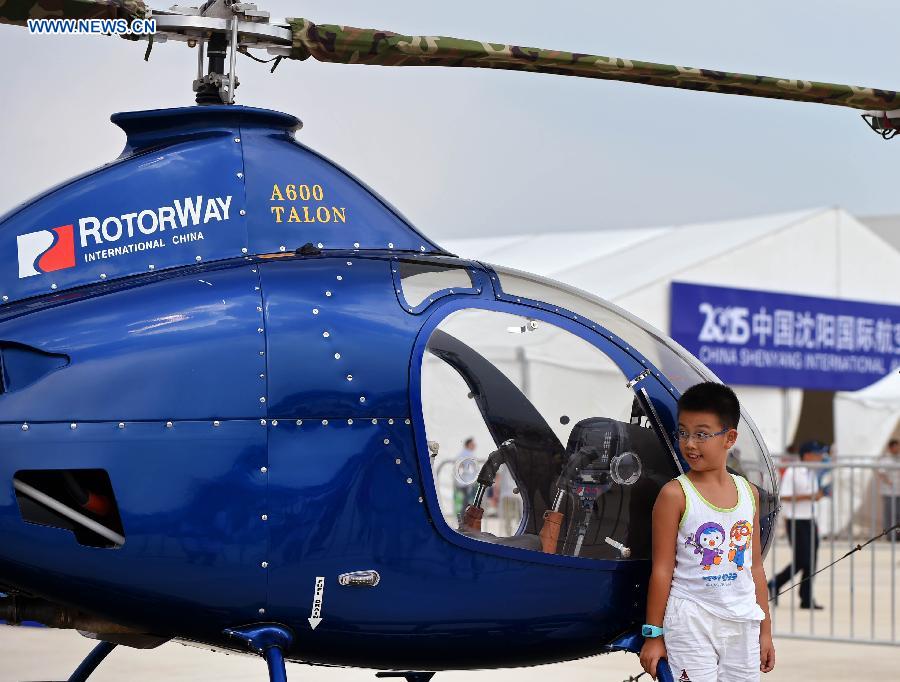 A boy poses with a helicopter at the opening ceremony of the 2015 Shenyang Faku International Flight Convention, in Faku County of Shenyang, capital of northeast China's Liaoning Province, Aug. 20, 2015.