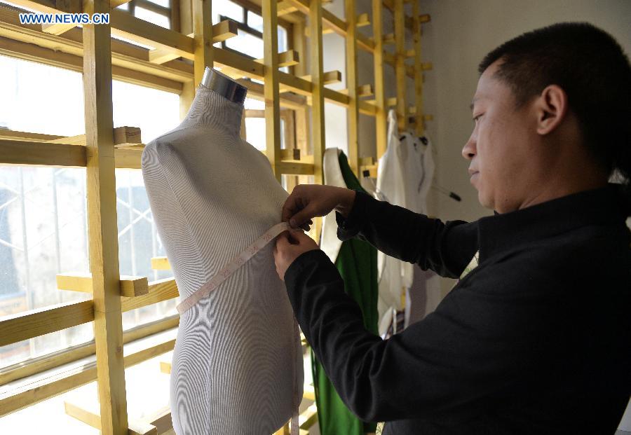 Genqoi Tashi measurs a model for his designs in Lhasa, capital of southwest China's Tibet Autonomous Region, Aug. 12, 2015.