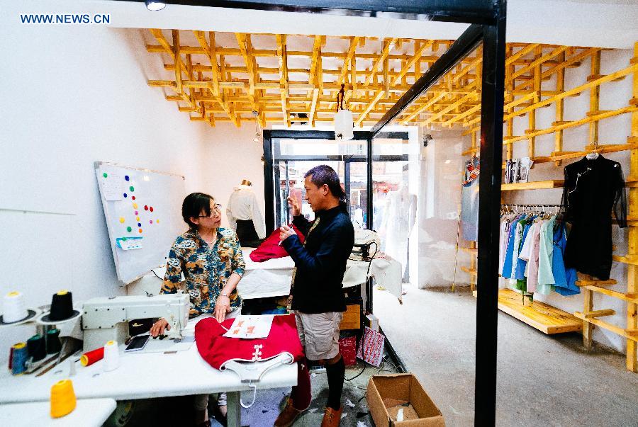 Genqoi Tashi explains his design to a tailor in Lhasa, capital of southwest China's Tibet Autonomous Region, Aug. 12, 2015.