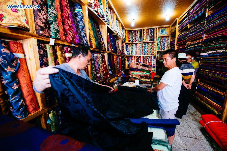 Genqoi Tashi selects cloth for his designs in Lhasa, capital of southwest China's Tibet Autonomous Region, Aug. 16, 2015. 