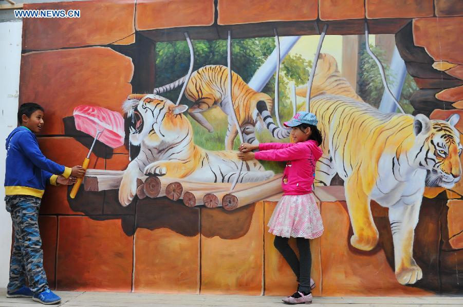 Two kids pose for photos during an exhibition of 3D trick art in Lhasa, capital of southwest China's Tibet Autonomous Region, Aug. 20, 2015. 