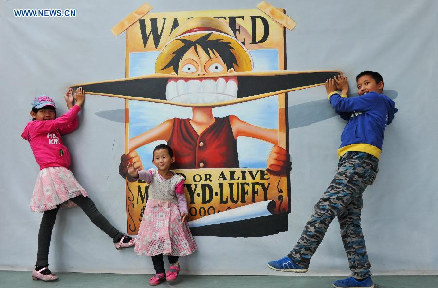 Three kids pose for photos during an exhibition of 3D trick art in Lhasa, capital of southwest China's Tibet Autonomous Region, Aug. 20, 2015. 