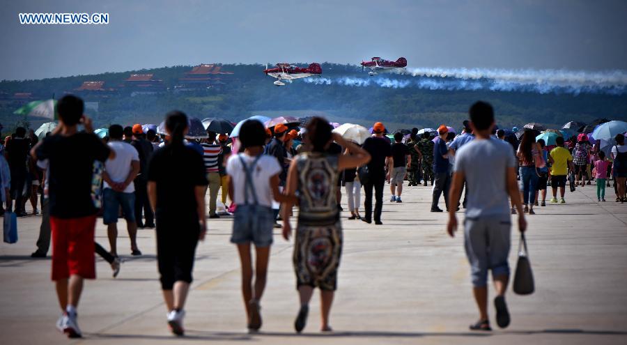 The audience watch the low altitude flight performance at the 2015 Shenyang Faku International Flight Convention, in Faku County of Shenyang, capital of northeast China's Liaoning Province, Aug. 21, 2015.