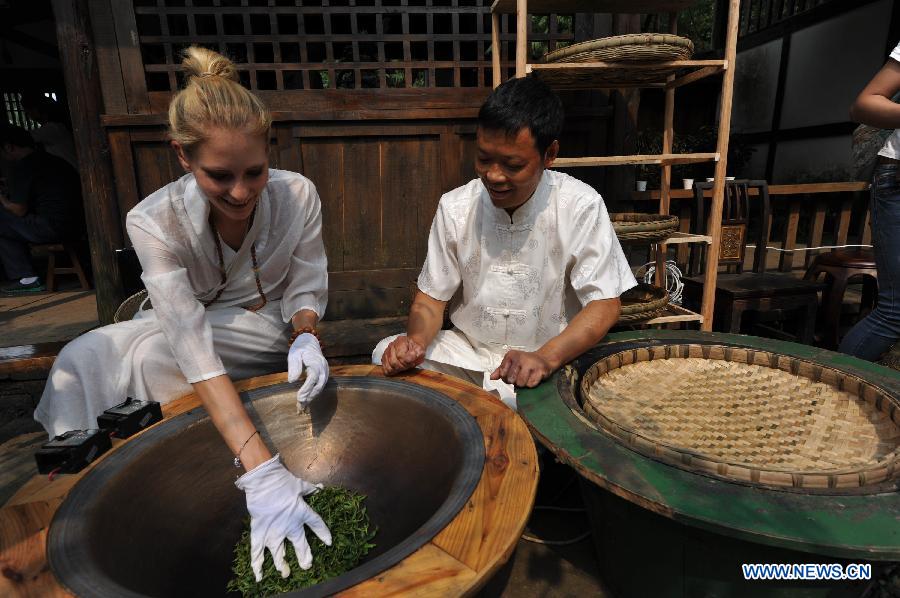 A German learns the techniques in making green tea at a tea planting garden in Emeishan City, southwest China's Sichuan Province, Aug. 23, 2015.