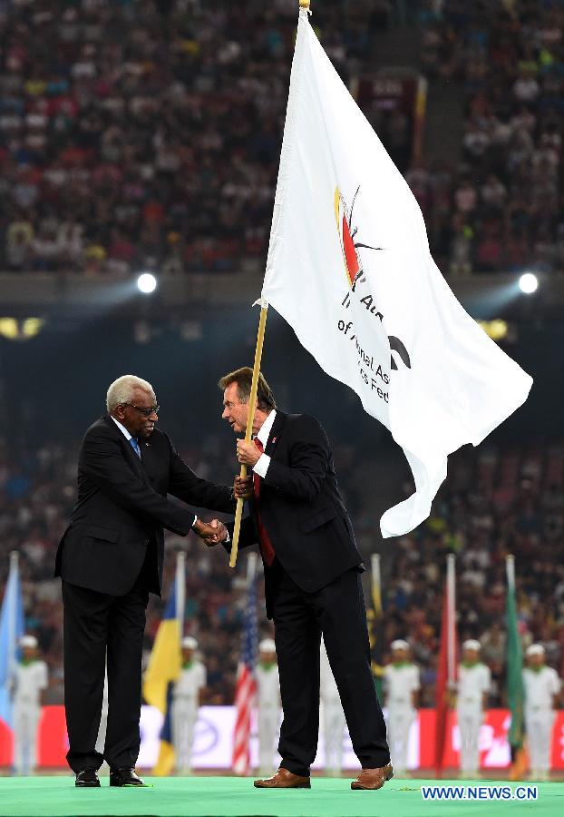 IAAF president Lamine Diack (L) hands over the IAAF flag to UK Athletics (UKA) president Lynn Davies during the closing ceremony of the 2015 IAAF World Championships at the 'Bird's Nest' National Stadium in Beijing, capital of China, Aug. 30, 2015.
