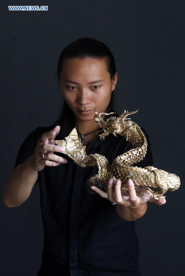 Qin Kun shows his origami works in the pattern of dragon in Guilin, south China's Guangxi Zhuang Autonomous Region, Sept. 6, 2015. 