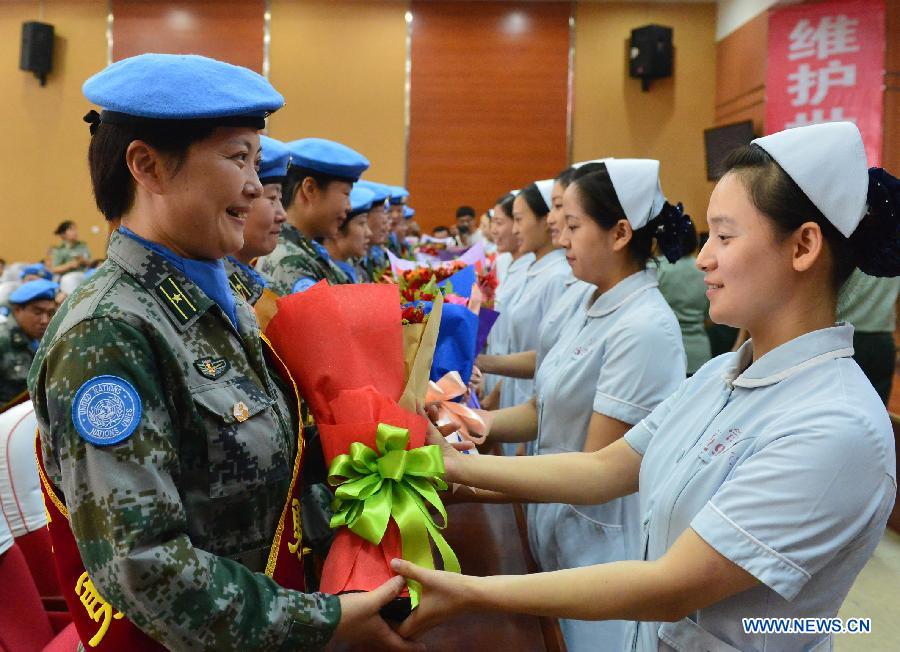 Medical staff members of Bethune International Peace Hospital offer flowers to colleagues who will leave for a 12-month United Nations peacekeeping mission in Liberia, in Shijiazhuang, capital of north China's Hebei Province, Sept. 7, 2015.