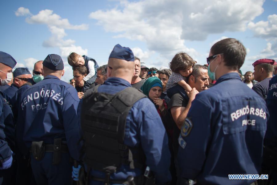 Hungarian police officers stand guard at a gathering point of illegal migrants near Roszke, a village on the Serbian-Hungarian border, Hungary, on Sept. 7, 2015.