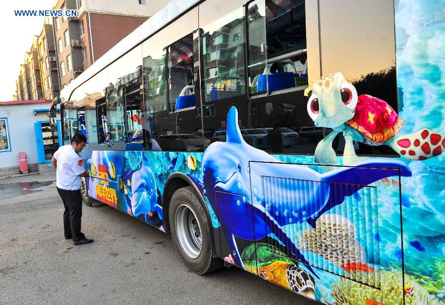 Bus driver Gu Zhenyu cleans his ocean theme bus in Changchun, northeast China's Jilin Province, Sept. 14, 2015.