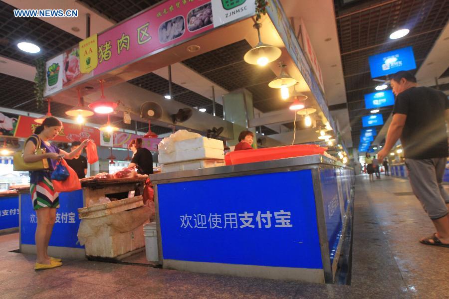 People purchase pork at a market in Wenzhou, east China's Zhejiang Province, Sept. 14, 2015. 