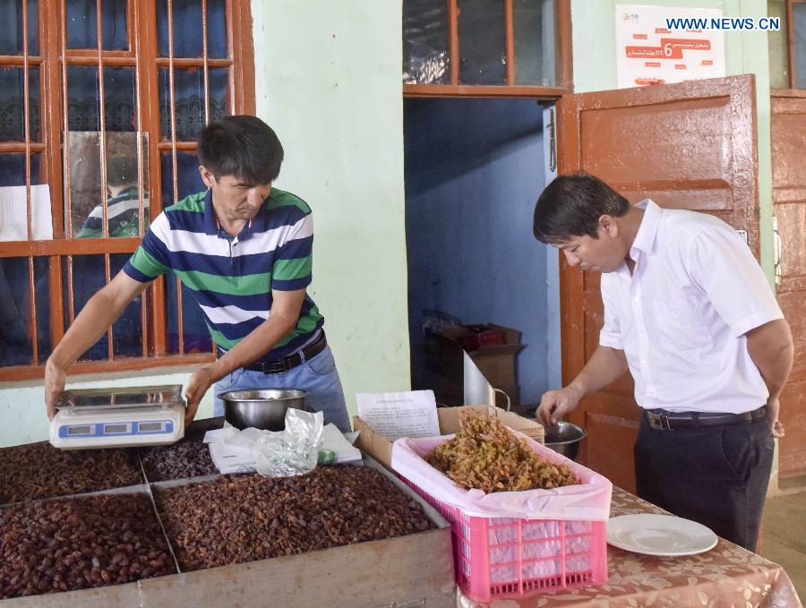 Pataer Keyimu introduces (L) dried grapes to a customer at home in the Grape Valley of Turpan, northwest China's Xinjiang Uygur Autonomous Region, Sept. 7, 2015. 