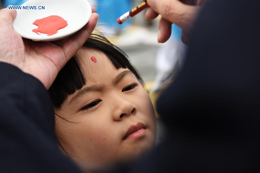 A girl gets a red dot on her forehead (which is called opening the wisdom eye) during a first writing ceremony in Guiyang, capital of southwest China's Guizhou Province, Sept. 28, 2015. 